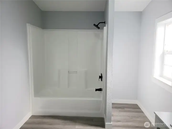 Another View of the Primary Master Bath Room Showing  New Shower Tub Combination, Paint, Trim and Vinyl Plank Flooring.
