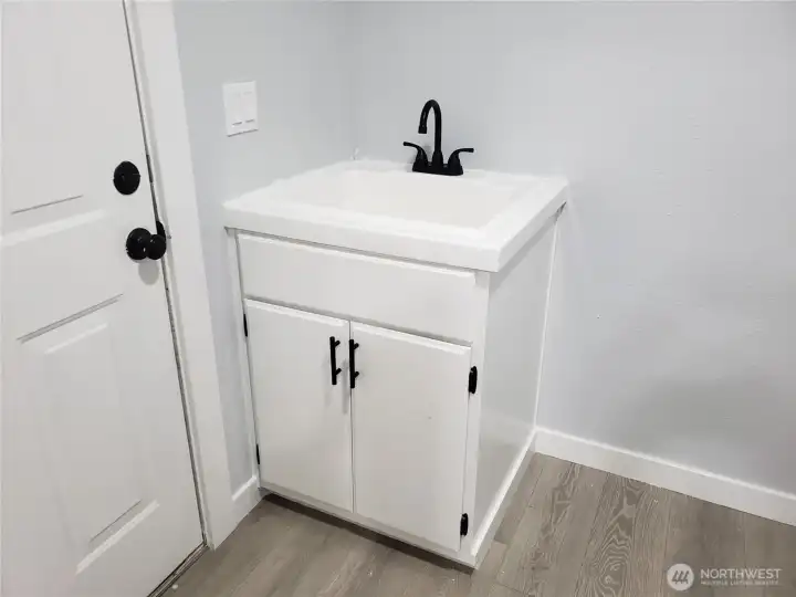 Nice Utility Room with a New Deep Utility Sink Vanity, Faucet, Paint, Trim, And Vinyl Plank Flooring.