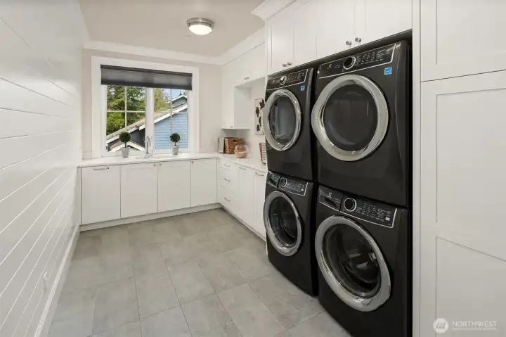 The laundry room is equipped with a double stack washer and dryer, providing efficient use of space and the ability to handle multiple loads simultaneously. Ample counter space is available in the laundry room, making it convenient for folding clothes. Additionally, there are drawers designed for storage.