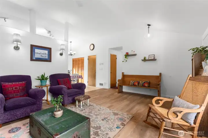 Open living area with vaulted ceilings, durable flooring, and clear sightlines to the dining and kitchen spaces.