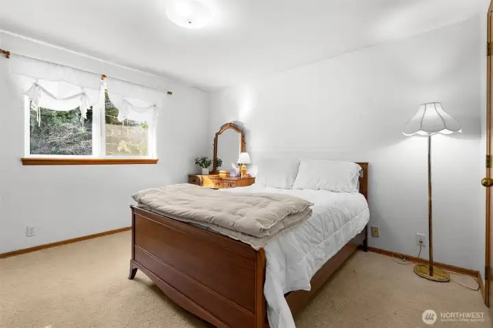Primary bedroom with carpet flooring, natural light, and direct access to a private en-suite bath.