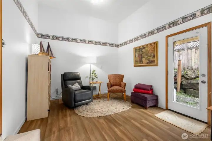 Finished bonus room with LVP flooring, flexible seating layout, and step-up access from the main house.