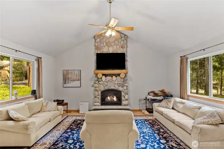 Inviting living space featuring a beautiful river rock fireplace and rustic log mantel.