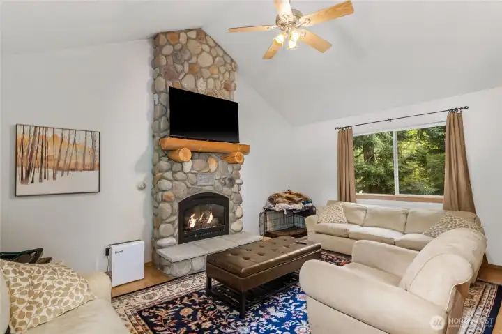 Spacious living room boasting vaulted ceilings and a floor-to-ceiling river rock fireplace.