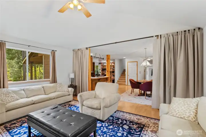 Warm, open living room with vaulted ceilings and a beautiful river rock fireplace with log mantel, just off the dining area.