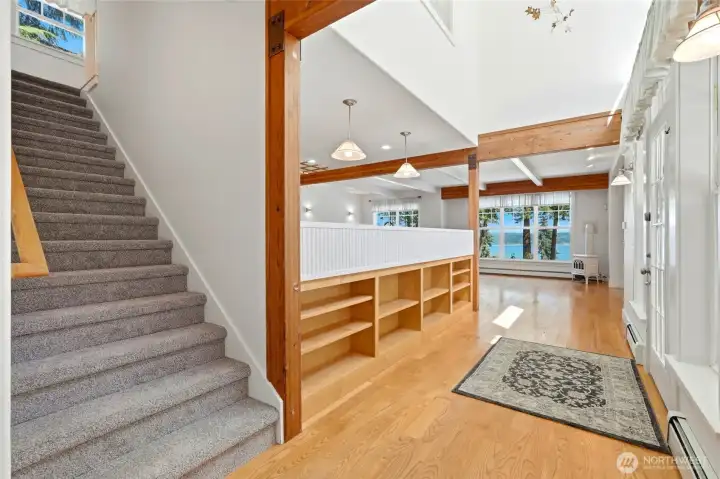 Welcoming entryway featuring built-in shelving, hardwood floors, and a bright, open layout leading to stunning water views.