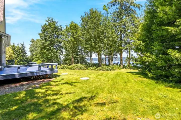 A beautiful blend of open lawn, mature trees, and water views offers the perfect balance of privacy and scenery, with the opportunity to reclaim even more usable yard space by cutting back the blackberry bushes.