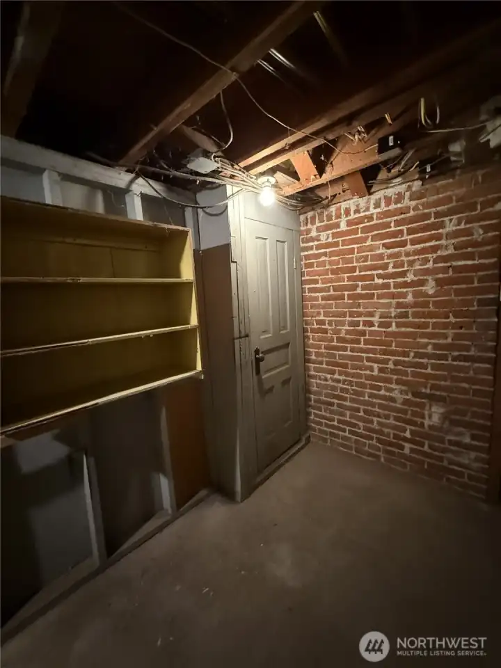 Basement with shelving on left side and door to where the old coal burning furnace and shoot used to be.