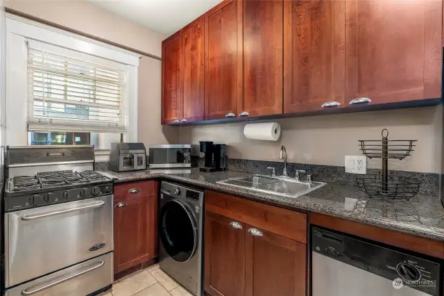 The kitchen boasts elegant granite countertops, modern stainless steel appliances, and a high-performance gas range—perfect for both everyday cooking and entertaining