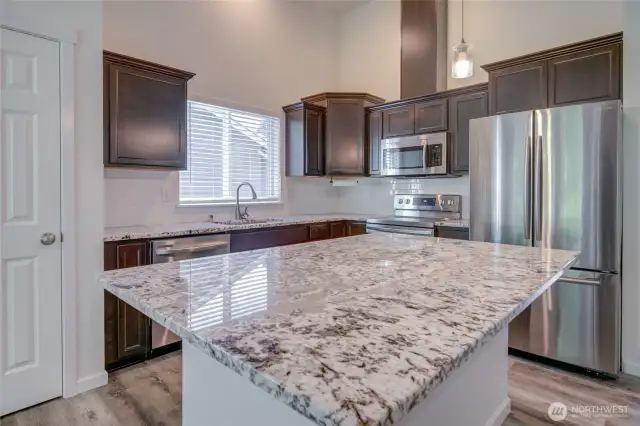 Kitchen has beautiful slab stone countertops, stainless steel appliances and a pantry closet.