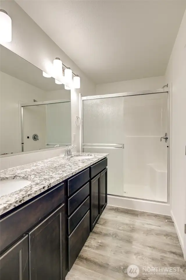 Primary bath has a step in shower and dual sinks.