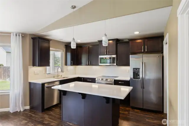 Kitchen features stainless steel  appliances, white quartz countertops, and glass mosaic backsplash