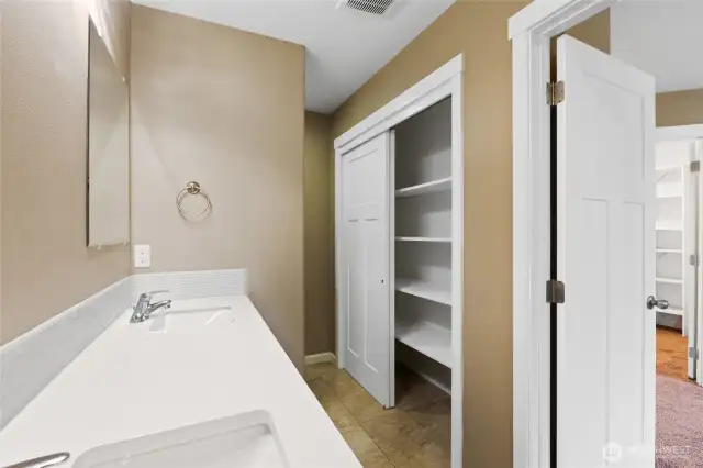 Primary bathroom with large linen closet and toilet hidden behind wall for added privacy