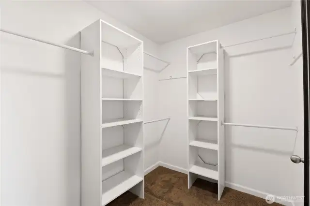 Primary bedroom walk in closet with closet organizer system