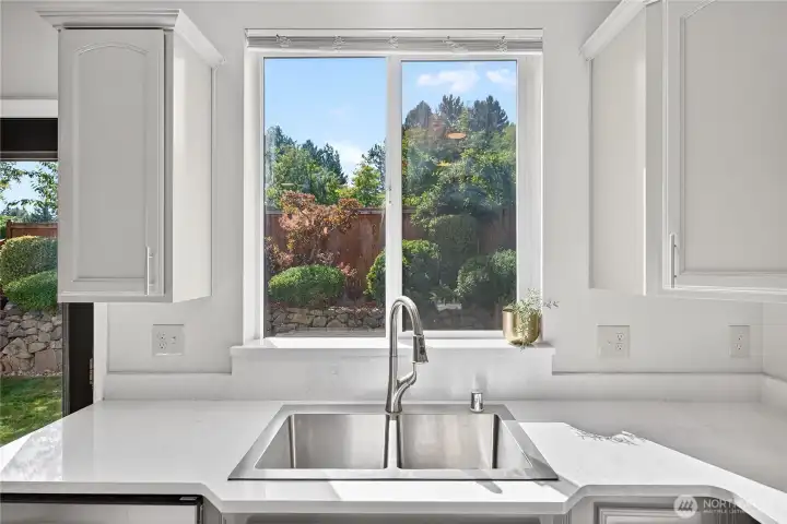 Enjoy serene backyard views with mature landscaping from the kitchen sink window