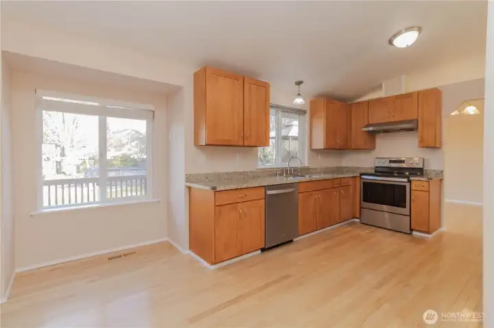 Sweeping view of kitchen with eating space and bright windows looking out over the back yard.