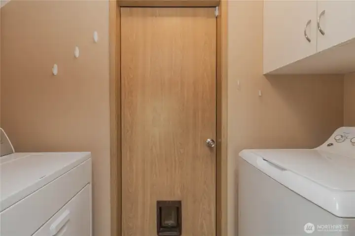 Laundry room with door to garage and small animal door. Washer and dryer stay.