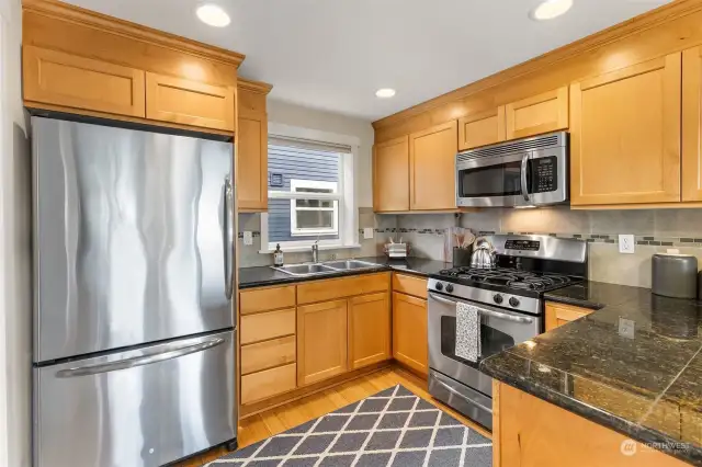 The kitchen is a well designed space with an eat-in peninsula, gas range, stainless steel appliances, granite countertops, and a spacious walk-in pantry.