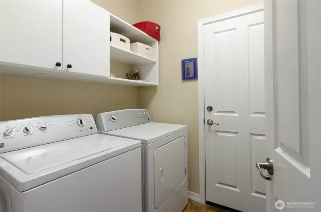Utility room has added cabinet storage.  Washer and dryer stay with the home.  Door leads to extended 2 car garage.