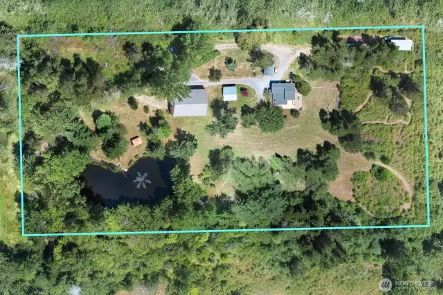 Aerial drone photo shows property lines and layout of buildings and pond with soothing aeration fountain.