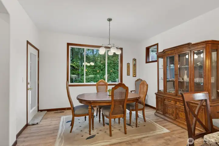 Spacious dining room directly connected to the kitchen, featuring an exterior door providing convenient access to the inviting backyard space.