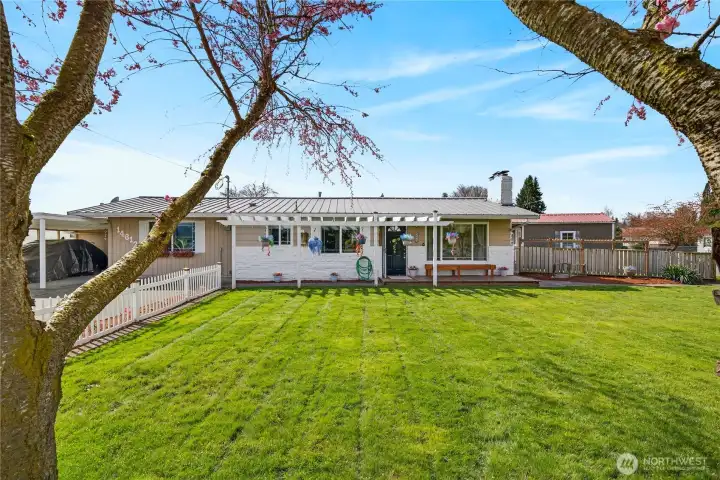 Charming single-level home with a spacious yard, covered patio with pergola, and inviting outdoor space perfect for relaxing or entertaining.