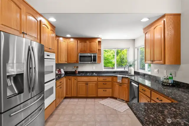 Spacious kitchen with ample cabinet storage, granite countertops and double ovens.