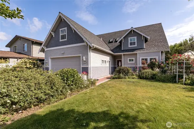 Road side of the Custom home with beautiful flower gardens.  Greenhouse on the right behind the rose trellis