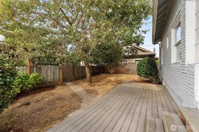 The back yard features a deck area with privacy from mature oak trees