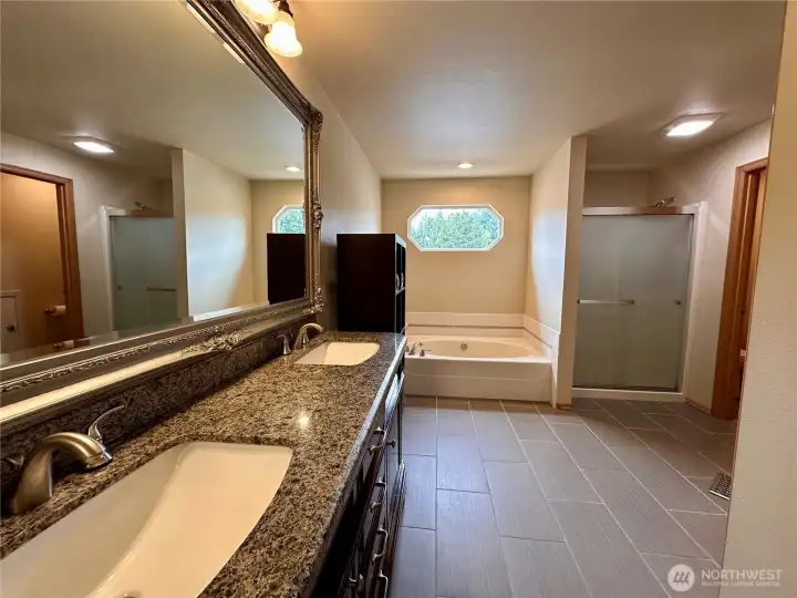 5 piece master bathroom that includes a granite topped double vanity, tile floors, large tub, separate shower, with private toilet room and a walk-in closet.