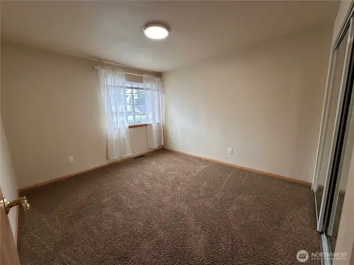 Secondary bedroom on the front side of the home with a large closet with mirrored doors to help you get ready in the morning.