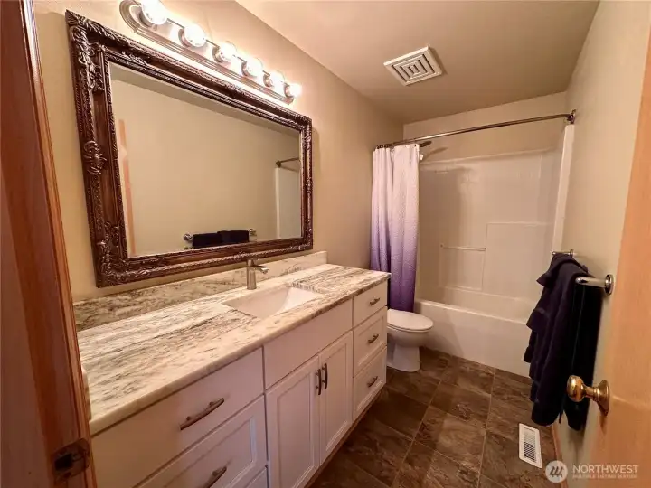 Upstairs bathroom with marble countertops and a shower/tub combo for the secondary bedrooms.