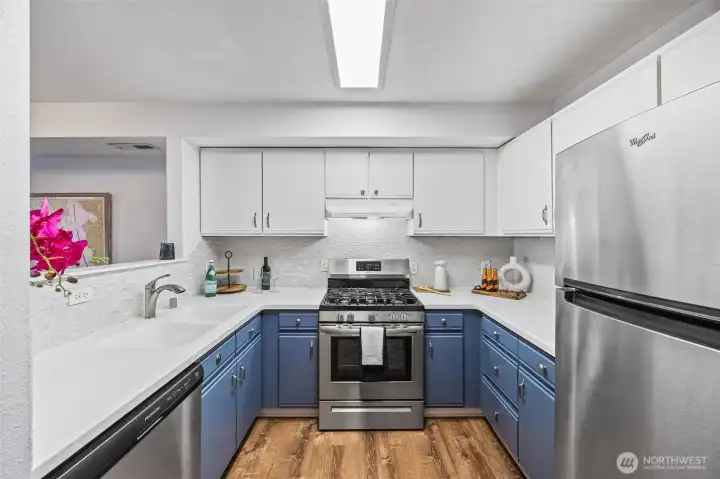 Renovated kitchen with deep slate-blue cabinetry, white quartz counters, and a bright coastal backsplash.