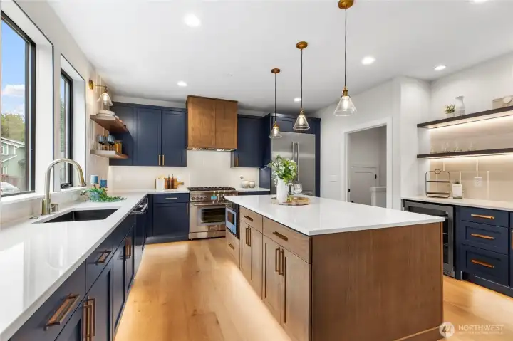 This kitchen is a showstopper, with its bold navy and wood cabinetry accented by sleek brass hardware and glowing pendant lights. The expansive island offers both style and function, perfect for prepping meals or gathering with friends. Flooded with natural light and anchored by warm wood floors, the space feels effortlessly elegant and inviting.