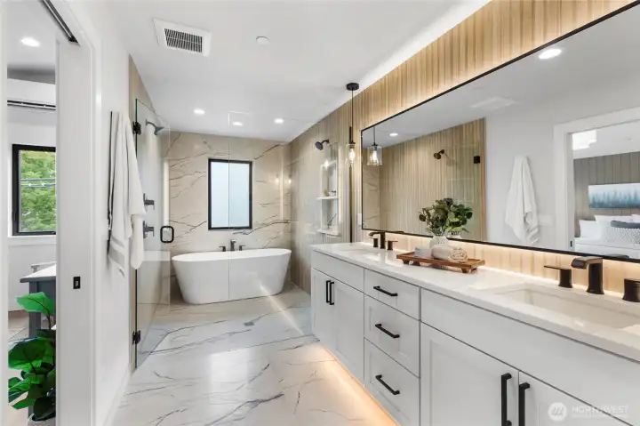 This luxurious primary bathroom features a double showerhead setup, perfect for a spa-like experience with customizable comfort and convenience. The sleek black fixtures and glass enclosure elevate the space with modern sophistication and functionality.