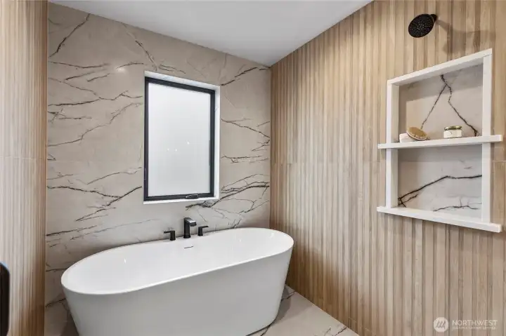 This freestanding bathtub makes a bold statement with its sculptural form and matte black fixtures, set against a backdrop of elegant marble tile. It’s the perfect centerpiece for a serene soak, blending luxury and minimalist design in one refined moment.