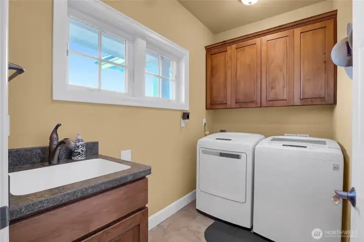 The spacious utility/laundry room on the main floor has an abundance of cupboards and a granite countered-sink.