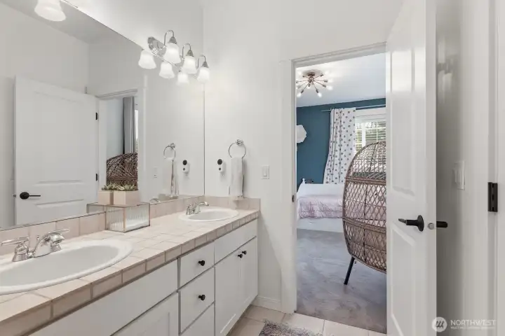 A second full bathroom upstairs with dual sinks, connecting two bedrooms.