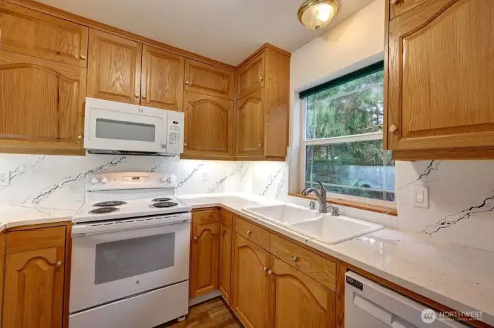 Updated kitchen with quartz counter tops looking out over the forest!