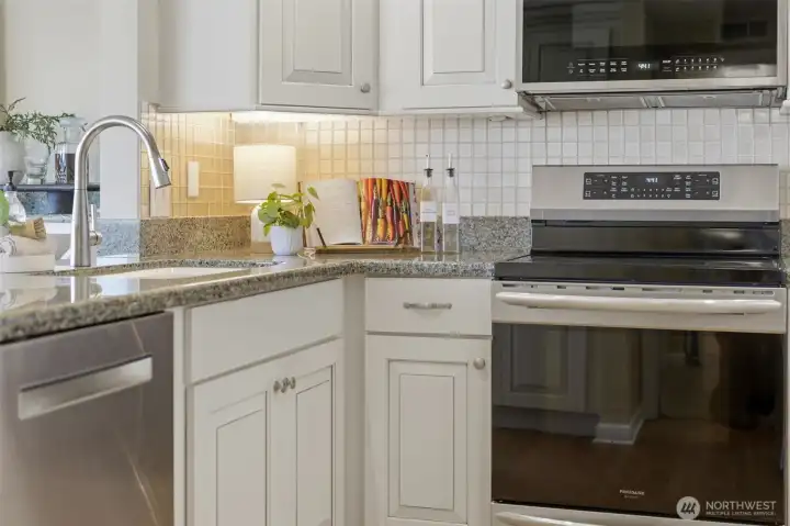 Updated kitchen featuring a newer dishwasher (2023), range (2022), microwave (2025), kitchen faucet (2020), and under-cabinet lighting Updated kitchen featuring a newer dishwasher (2023), range (2022), microwave (2025), kitchen faucet (2020), and under-cabinet lighting