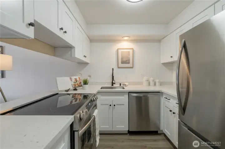 Fully remodeled kitchen featuring new cabinetry, quartz countertops, stainless steel appliances, new light fixture, and contemporary finishes throughout.