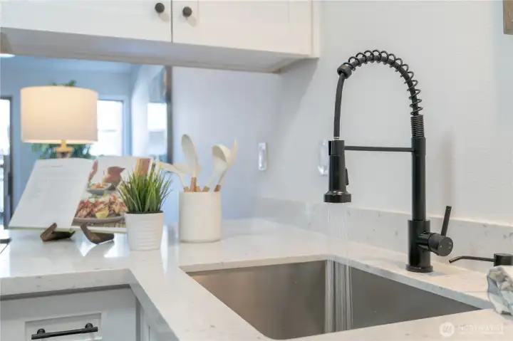 Stylish kitchen details include a deep stainless-steel sink and modern black pull-down faucet.