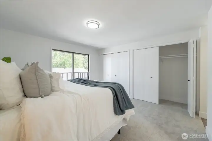 Spacious primary bedroom featuring double closets, abundant natural light, a new light fixture, and access to a private balcony.