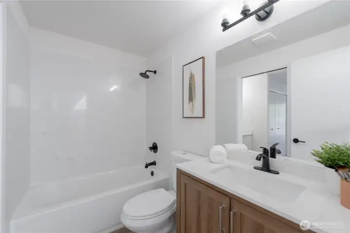 Fully remodeled upstairs bathroom featuring new tub/shower surround, modern vanity, updated fixtures, and luxury vinyl plank flooring.