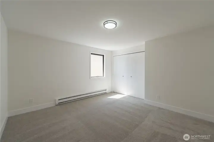 Spacious second bedroom upstairs with closet, new light fixture, and natural light.