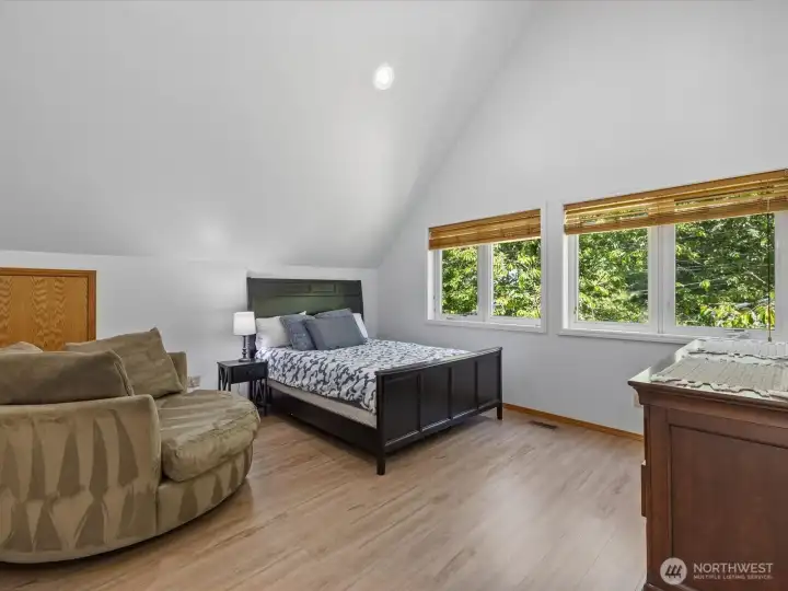 The upper level primary bedroom features vaulted ceilings and walk-in closet.