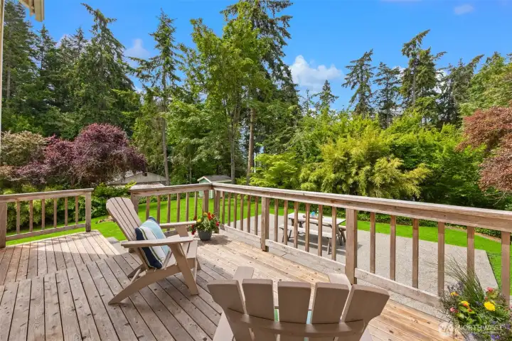 Sit and enjoy the peek water view with steps to a patio/entertaining space and the large, lush yard below.