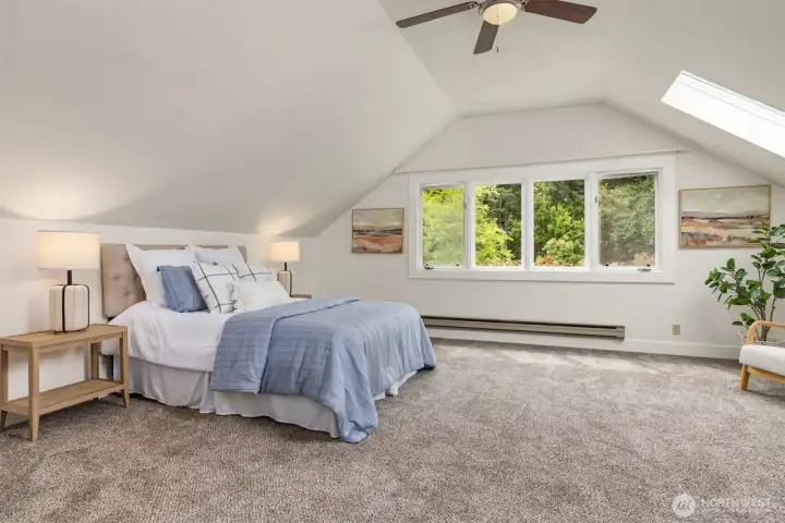 The spacious, vaulted primary bedroom enjoys skylights, large windows, and an ensuite bathroom.