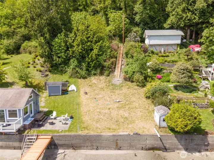 A closer aerial view highlights the ready-to-build homesite and the extensive work already completed. The property features a bulkhead, a three-bedroom septic system, completed wetland mitigation, and on-site water and electricity. Thoughtfully designed building plans position the future home to maximize views and enjoyment of the shoreline setting.