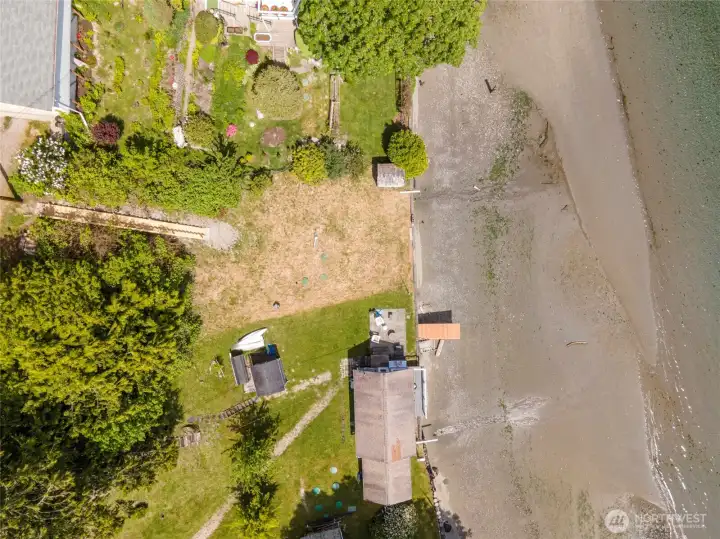 From above, you can appreciate the full scope of the property, extending from the shoreline to the wooded hillside beyond. The combination of waterfront access, open space, and natural surroundings creates a unique setting for your future home on Puget Sound.